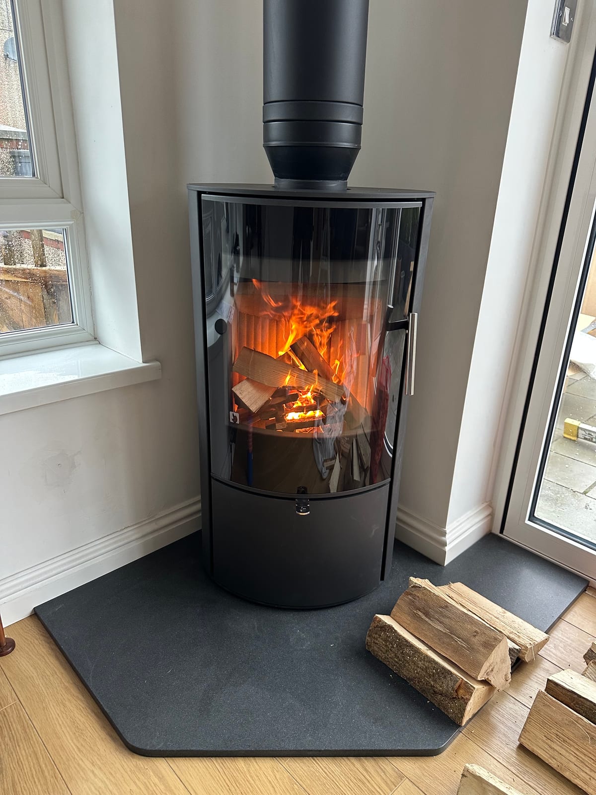 Modern black freestanding wood-burning stove with fire lit