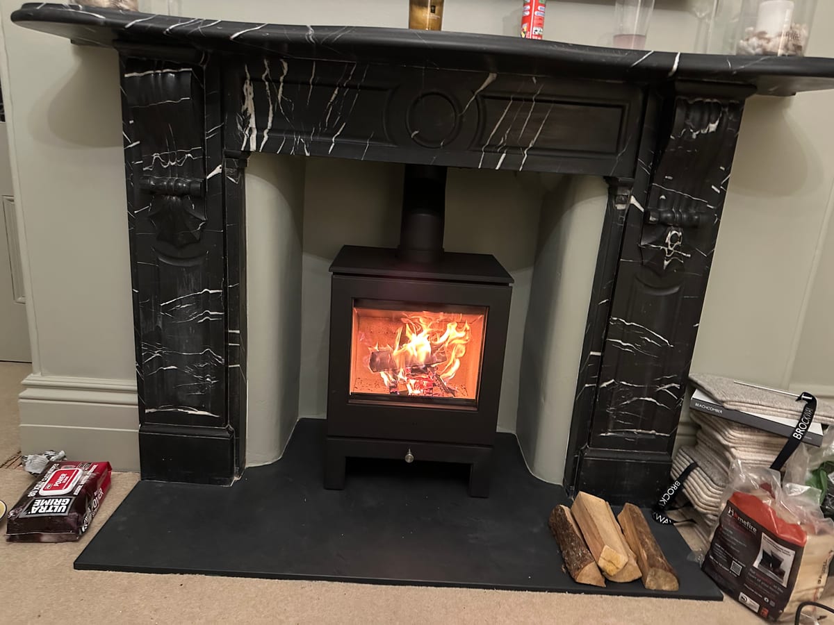 Black marble fireplace surround with modern wood-burning stove alight