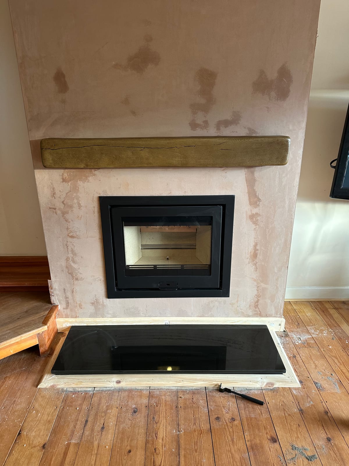 Contemporary inset stove with rustic timber mantel during fit-out
